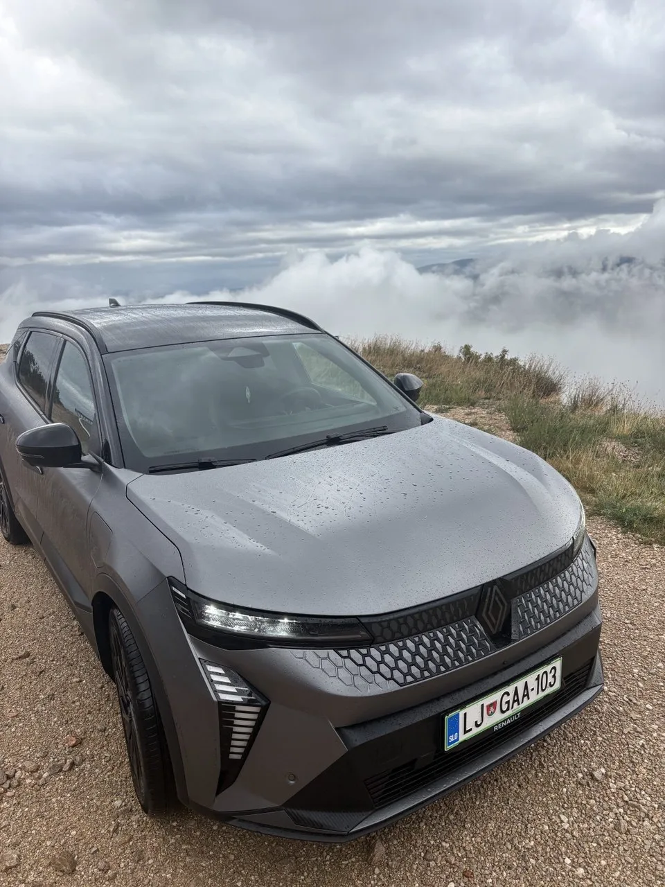 Renault Scénic E-Tech, sivi, pogled sprijeda sa strane iznad oblaka